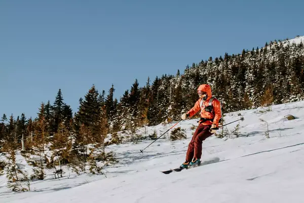 Female in red skis down Baldface Mountain, NH on a cold morning.