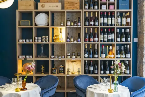 Restaurant dining area with tables set shelves filled with wine bottles and decor in the background