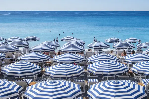 Beach with striped umbrellas and people near the water