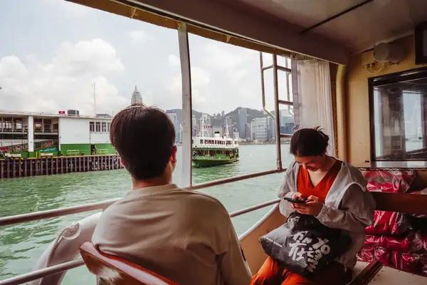 Two people on a boat passing other ferries on the water.