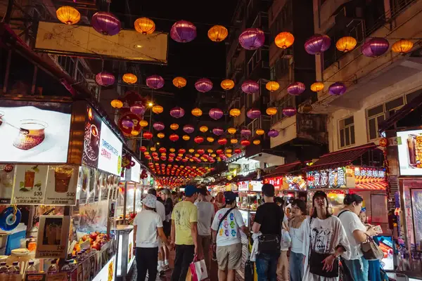 a large crowd shopping a stalls in a night market.