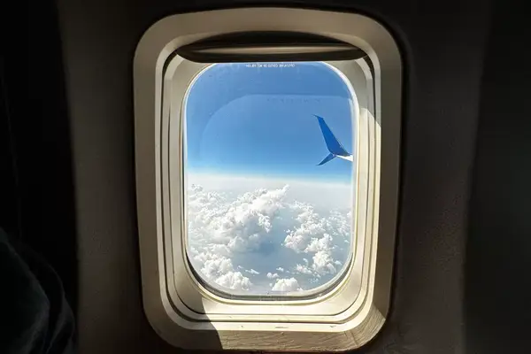 Clouds and airplane wing outside an airplane window 