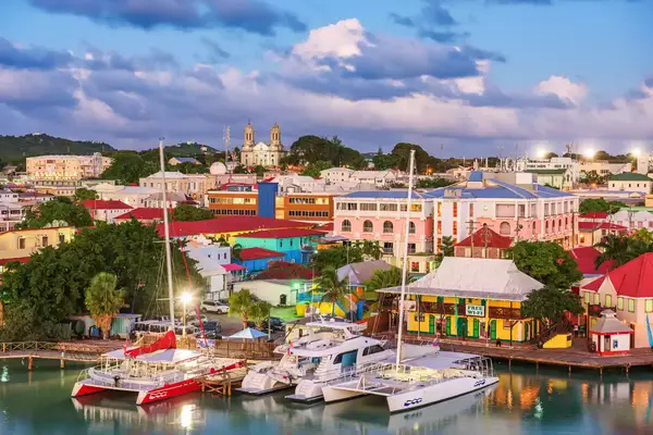 A waterfront view of a town with moored boats, colorful buildings, and a church in the background