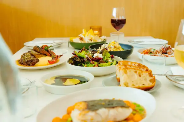Various dishes arranged on a table in a restaurant including salads bread and drinks in glasses