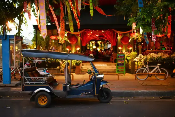small blue tuk tuk (small vehicle with three wheels) parked on street