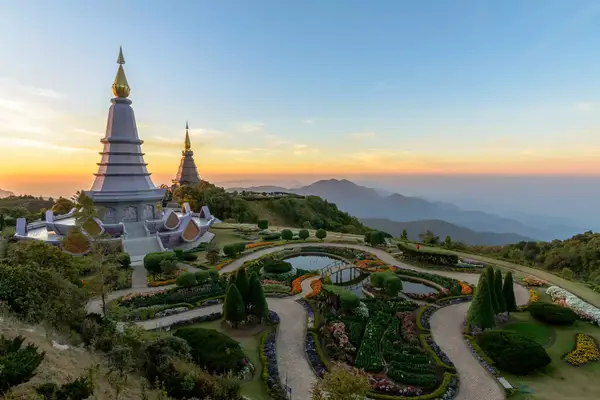 large pagoda on top of a mountain side with large winding pathway down at sunset