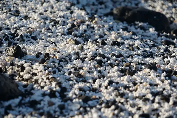 Close view of roughtextured sand resembling popcorn a rocky surface in the background