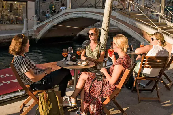 Women enjoying aperitifs by the canal in Venice, Italy