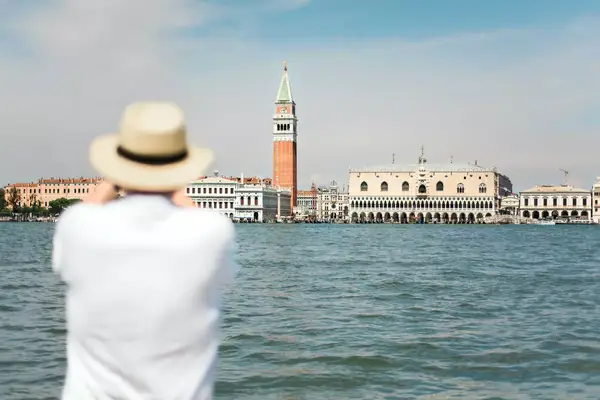 View of a man taking a photo of the Campanile di San Marco and the Doge