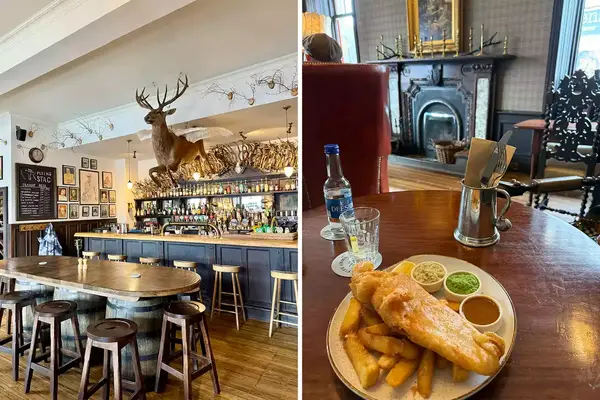 A pub interior with a bar and a mounted stag figure on the left, a plate of fish and chips on a wooden table near a fireplace on the right