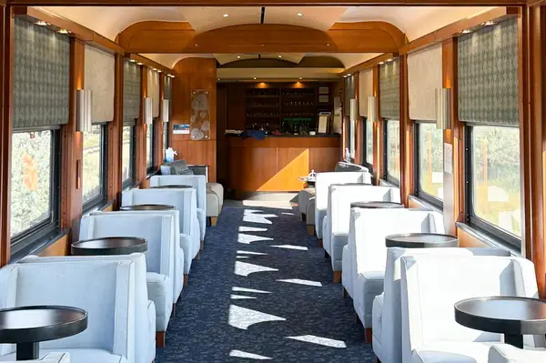 Luxurious interior of a train car with comfortable seating and a bar at the far end designed for passenger relaxation