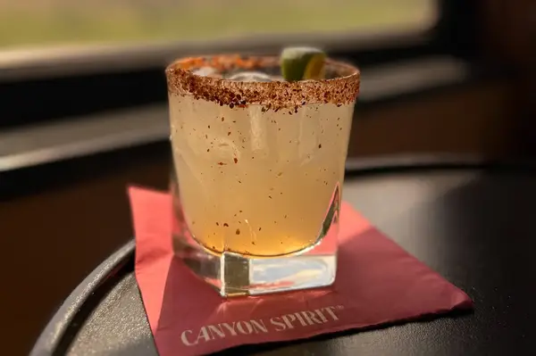 A seasoned cocktail on a napkin with the inscription Canyon Spirit lime garnish served on a table