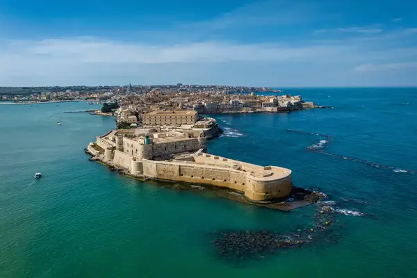 Aerial view of a historic coastal settlement surrounded by turquoise water
