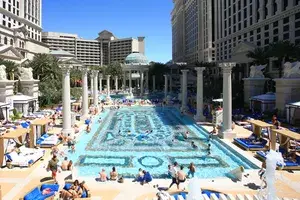 A luxurious outdoor pool area with columns and people relaxing, located in a Las Vegas hotel