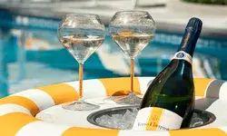 Two wine glasses and a bottle of Veuve Clicquot in a poolside setting