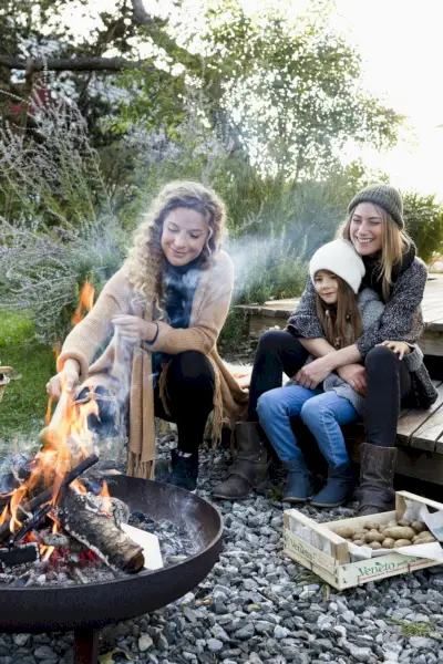 two women and girl sitting by fire pit, relaxing