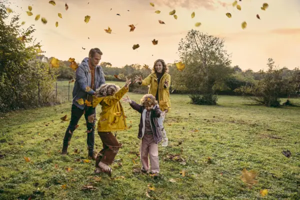 happy family playing with autumn leaves on a meadow