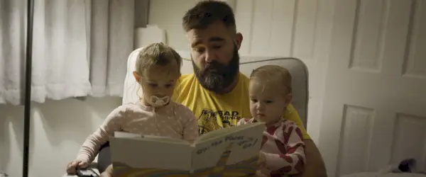 a person reading a book to two children