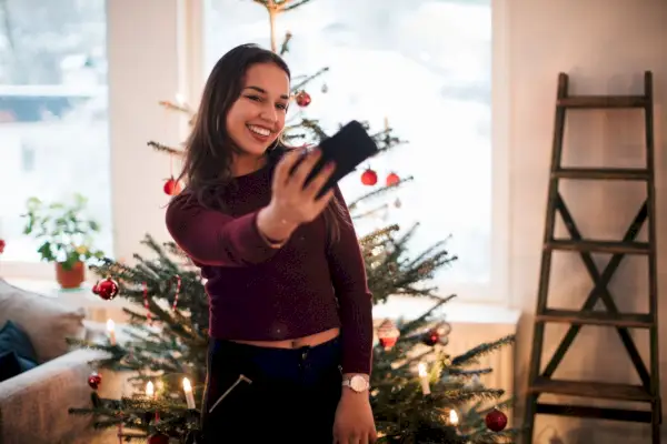 woman taking a selfie in front of a christmas tree