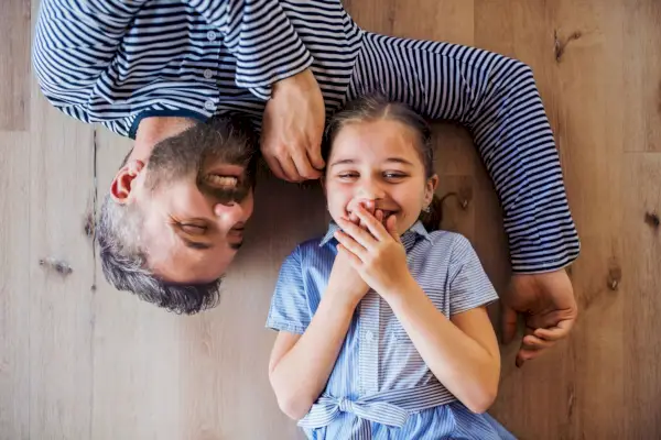 top view of mature father and small daughter lying on floor indoors at home