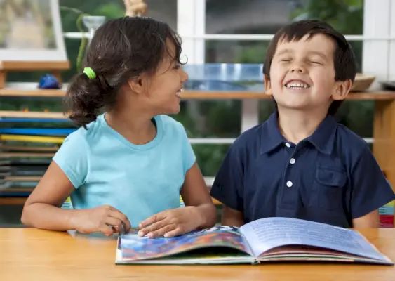 two laughing kids enjoying a book at school