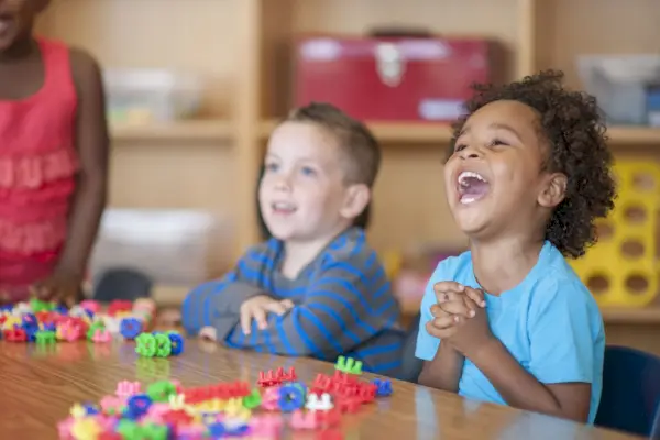two kids laughing at table in classroom