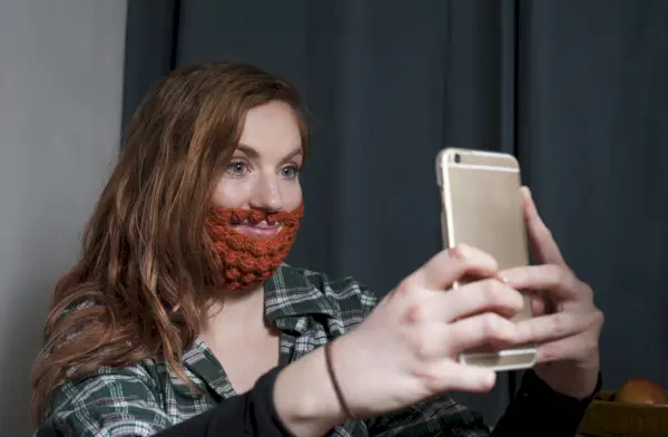 woman wearing red crochet beard taking a selfie for saint patrick