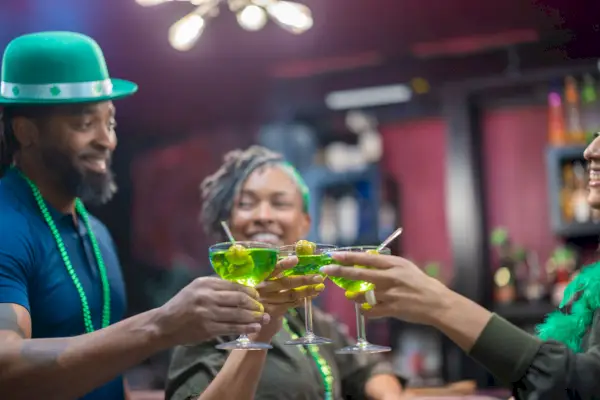 three friends clinking green martinis on st patrick
