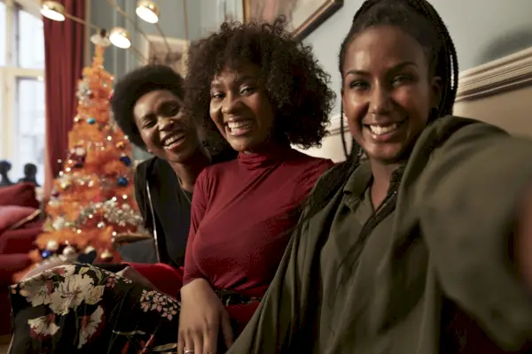 three young women making selfie in sofa by christmas tree at home