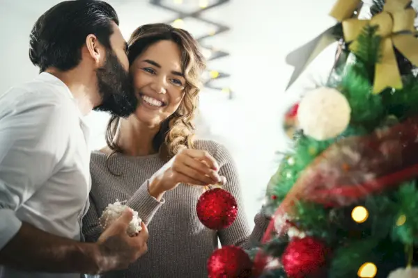 closeup side view of late 20s mixed race decorating a christmas tree in their living room