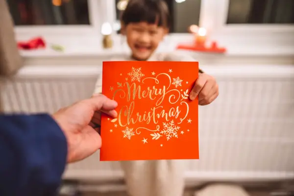 personal perspective of a dad receiving a christmas card given by her lovely cheerful daughter in christmas at home concept of christmas celebration with family at home