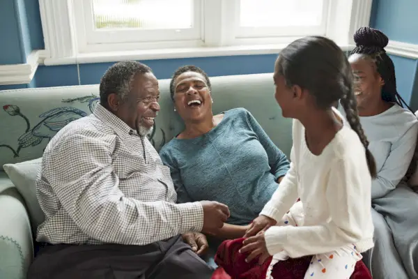 high angle view of cheerful grandparents talking with granddaughters while sitting on sofa at home