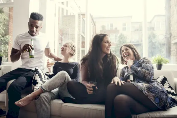 group of young people having a party, telling jokes, having a good time, celebrating, in a private home