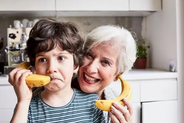 grandmother and grandson fooling around, using bananas as telephones, laughing