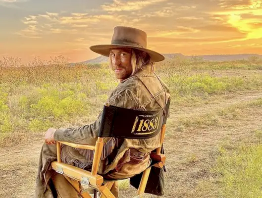 eric nelsen dressed as a cowboy while sitting on set of 1883