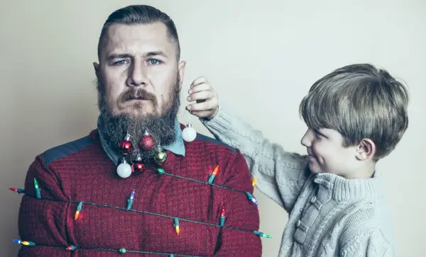 little boy having fun decorating his near agony full of despair very overwhelmed by holiday season dad as a christmas tree
