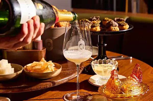 A table set with champagne being poured gourmet snacks and dessert items