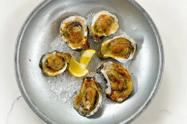Cooked oysters on a plate with lemon slices