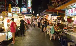 Crowded street market at night with food stalls and people dining