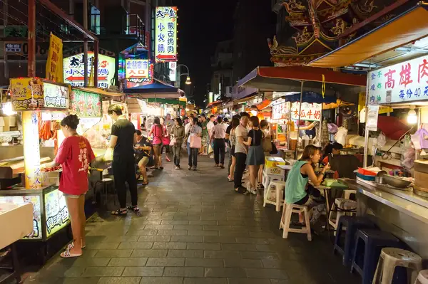 Crowded street market at night with food stalls and people dining
