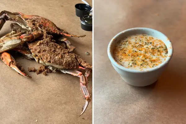 A cooked crab on the left and a cup of creamy soup or bisque on the right presented side by side on a brown surface