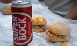 Can of Super Bock beer and sandwiches on paper