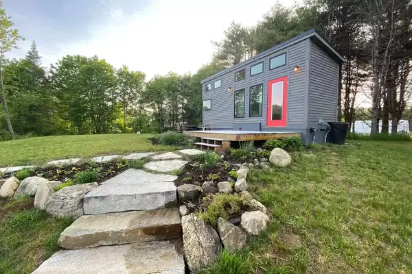 Grey exterior of tiny home with red door