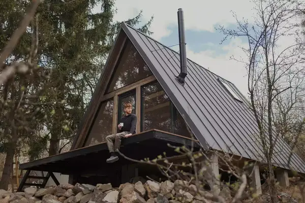 Young mid adult man with red hair sitting on a terrace of AirBNB and drinking coffee