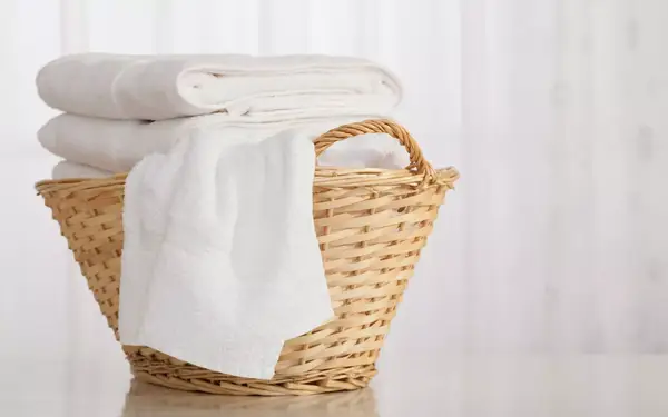 Studio shot of stack of white towels in Wicker Basket