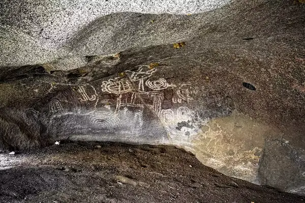 Ancient carvings on a rock face in a cave setting