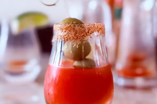 A Bloody Mary garnished with olives and served in a rimmed glass during a masterclass at a resort