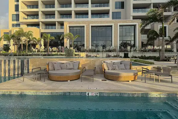 Poolside seating area at a luxury resort with lounges and a building in the background