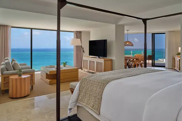 Luxury bedroom suite with ocean view, sitting area, and dining table