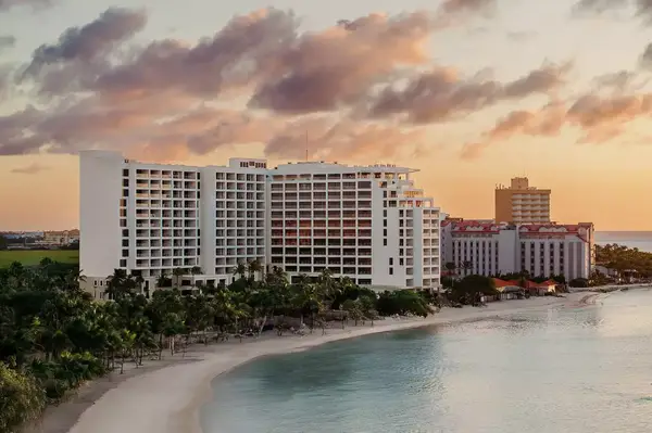 Beachfront resort with tall buildings and palm trees at sunset